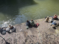 903622 Afbeelding van enkele personen die genieten van de zon op de werf langs de Oudegracht te Utrecht.